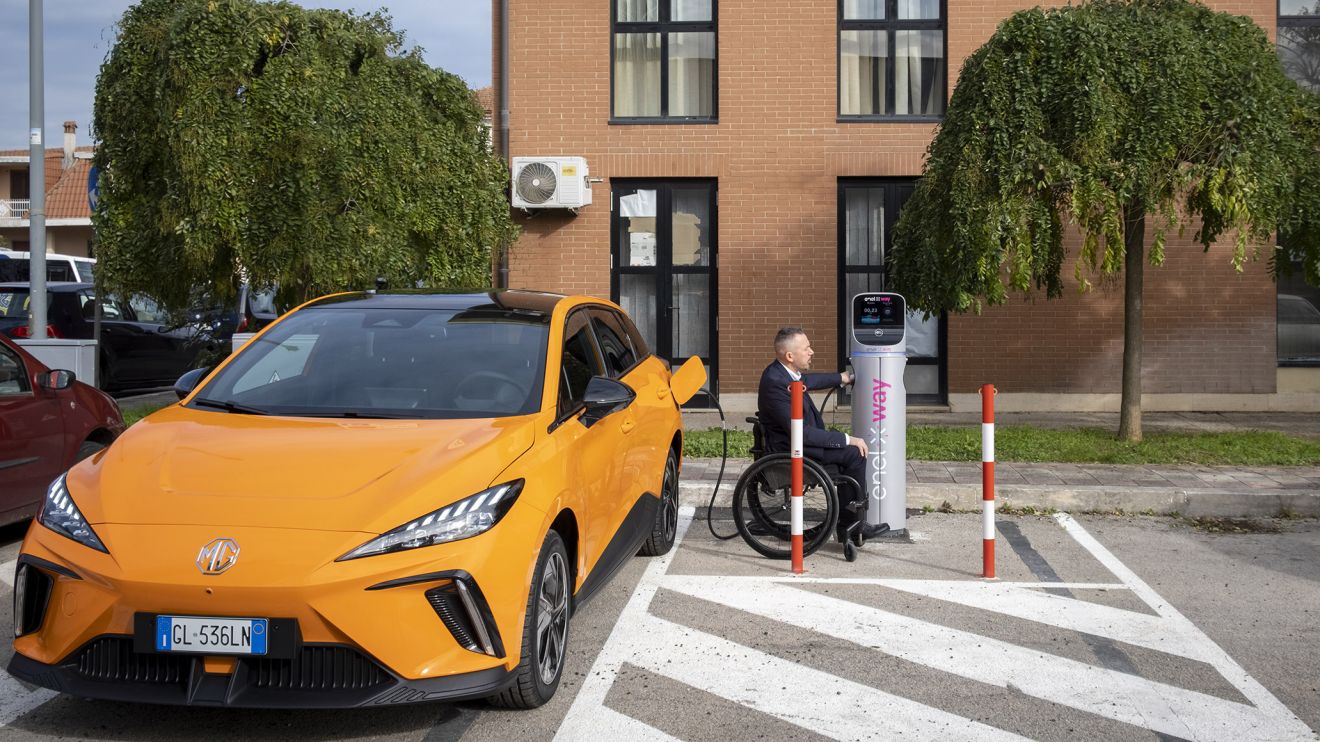 A wheelchair user charges his car at a charging port.